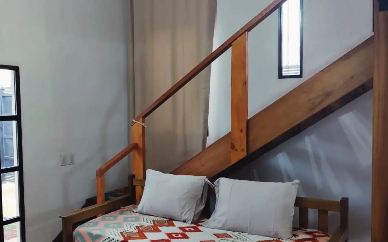 Sofá cama doble con escalera al entrepiso de madera y techos altos en loft Yvyra, Puerto Iguazú
