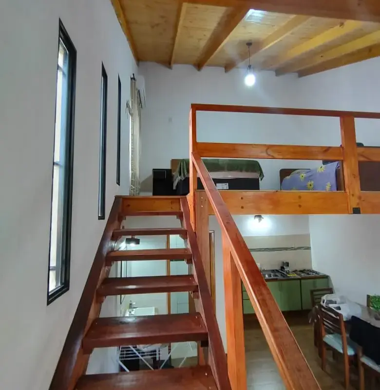 Escalera de madera al entrepiso con camas y techo alto en departamento loft Yvyra, Puerto Iguazú